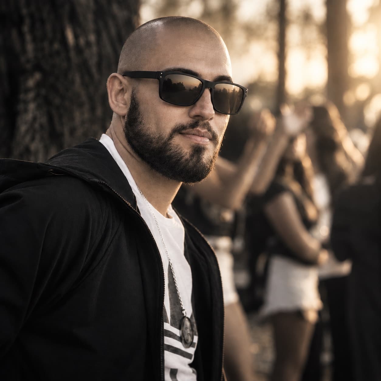 Portrait of Lostest in sunglasses, head shaved, low sun behind him